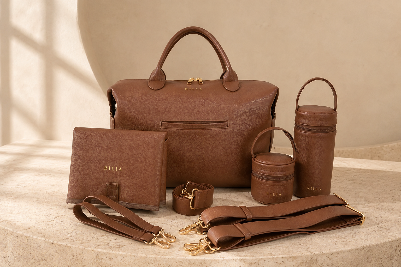 Das komplette RILIA Set in Cognac: Signature Bag, Wickelmatte, Bottle Bag, Schnullerbox und beide Trageriemen